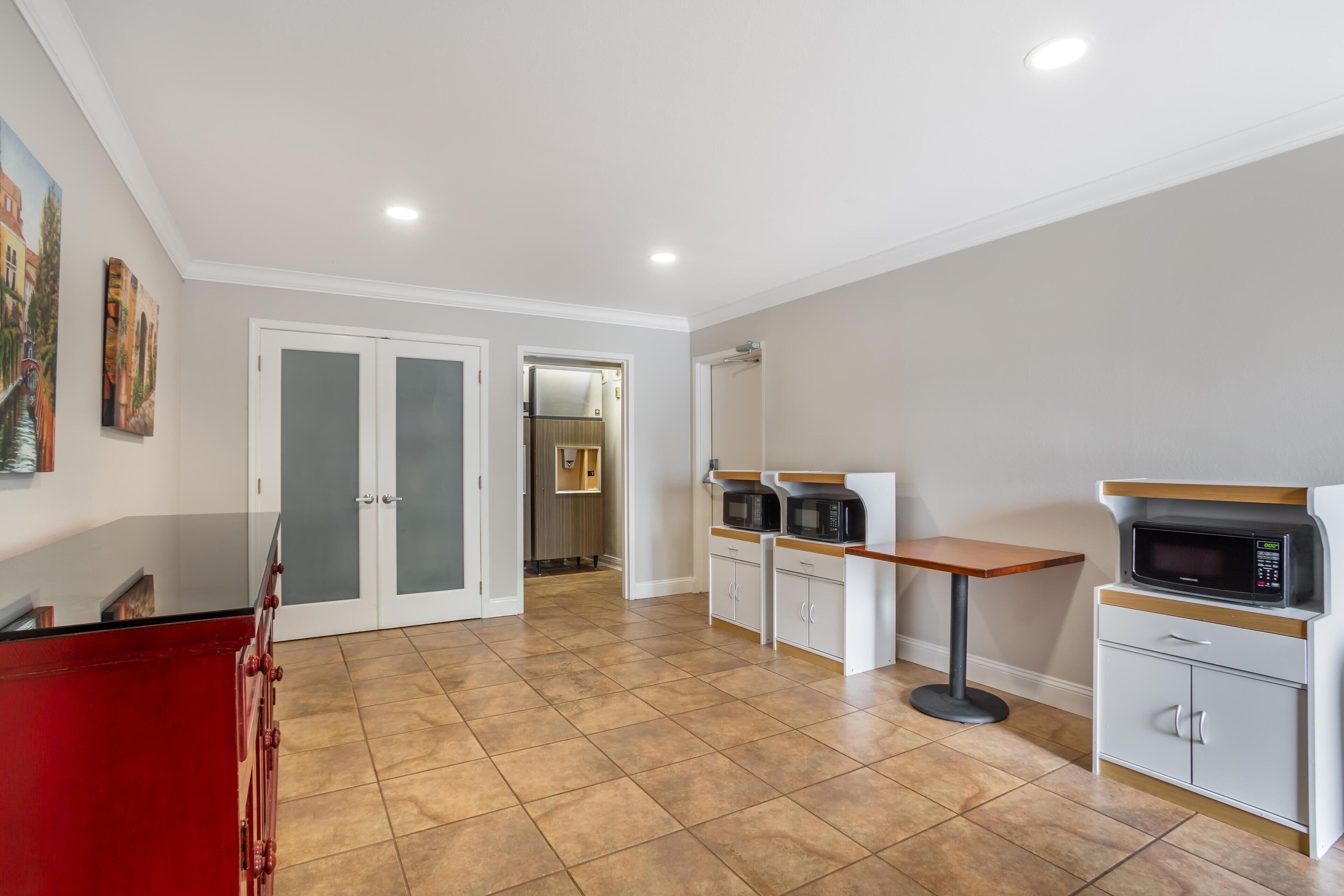 A spacious kitchen with a red countertop, white cabinets, and two microwaves.