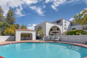 Relax by the serene pool surrounded by lush trees and comfortable lounge chairs.