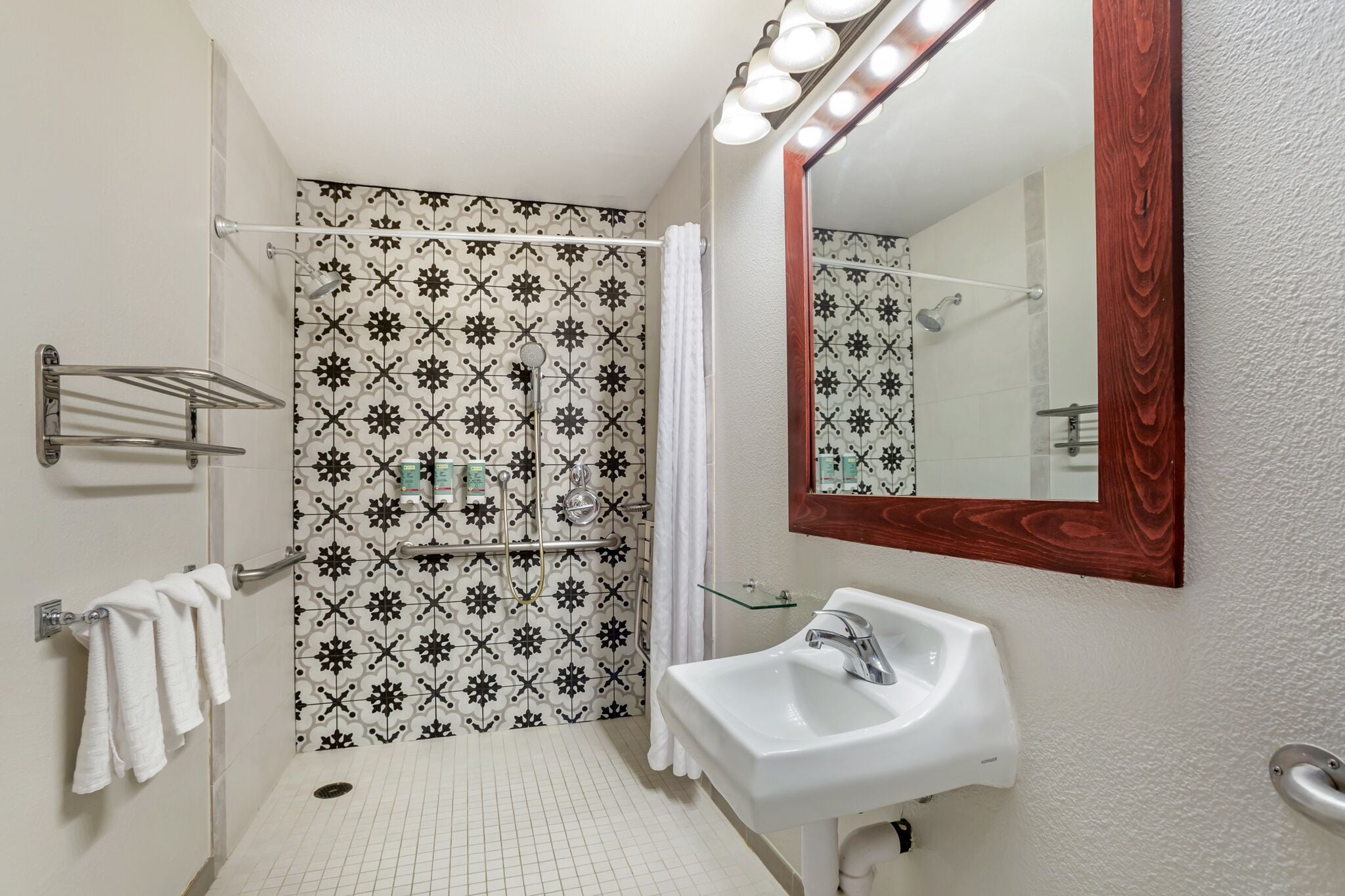 Une salle de bain équipée d’une douche, d’un lavabo, d’un miroir et d’un porte-serviettes.