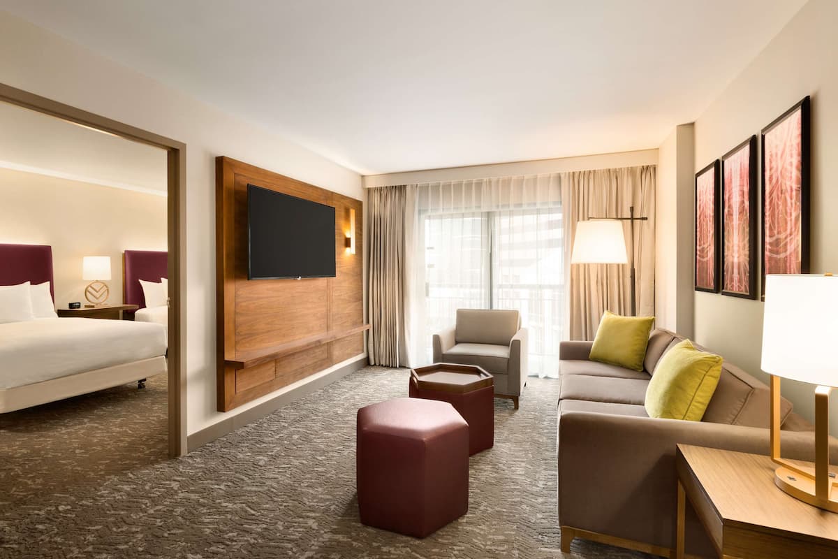Ein Hotelzimmer mit einem Bett, einer Couch, einem Couchtisch und einem an der Wand befestigten Fernseher.