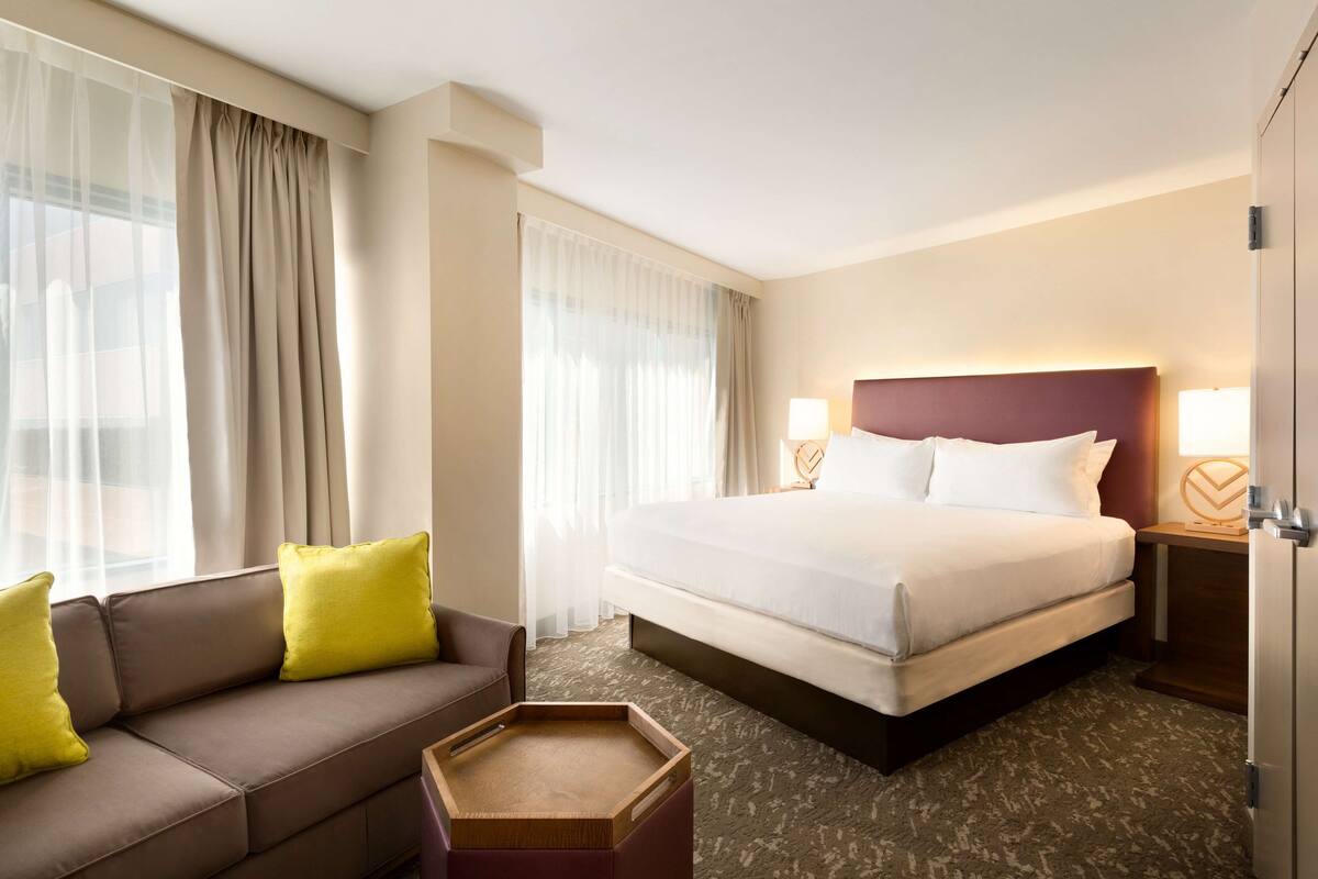 Ein Hotelzimmer mit einem Bett, einer Couch, einem Beistelltisch und einem kleinen Holztisch.