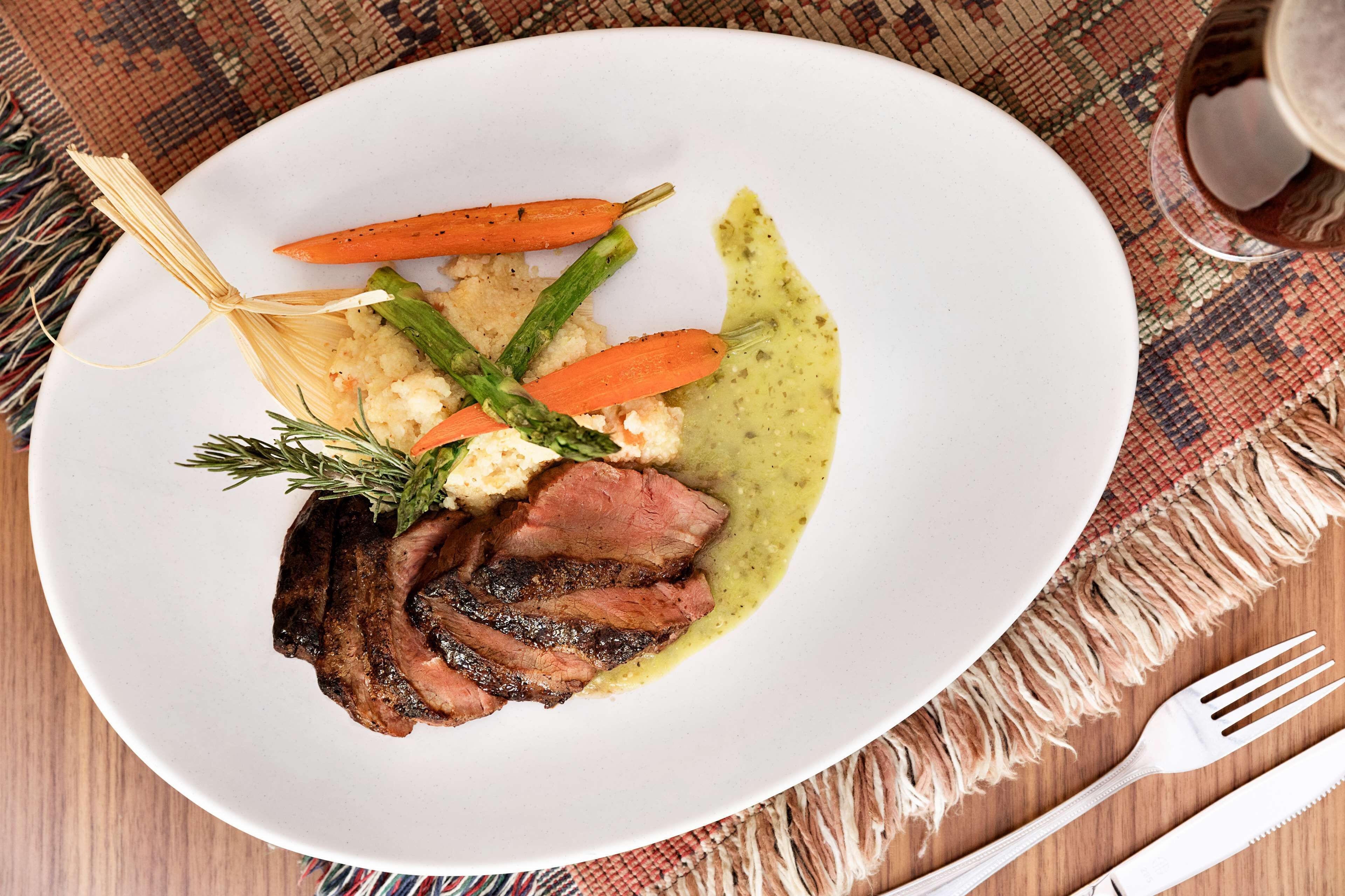 Un plato de comida con filete, zanahorias, espárragos y puré de papas.