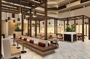 A spacious lobby with seating areas, a staircase, and hanging pendant lights.