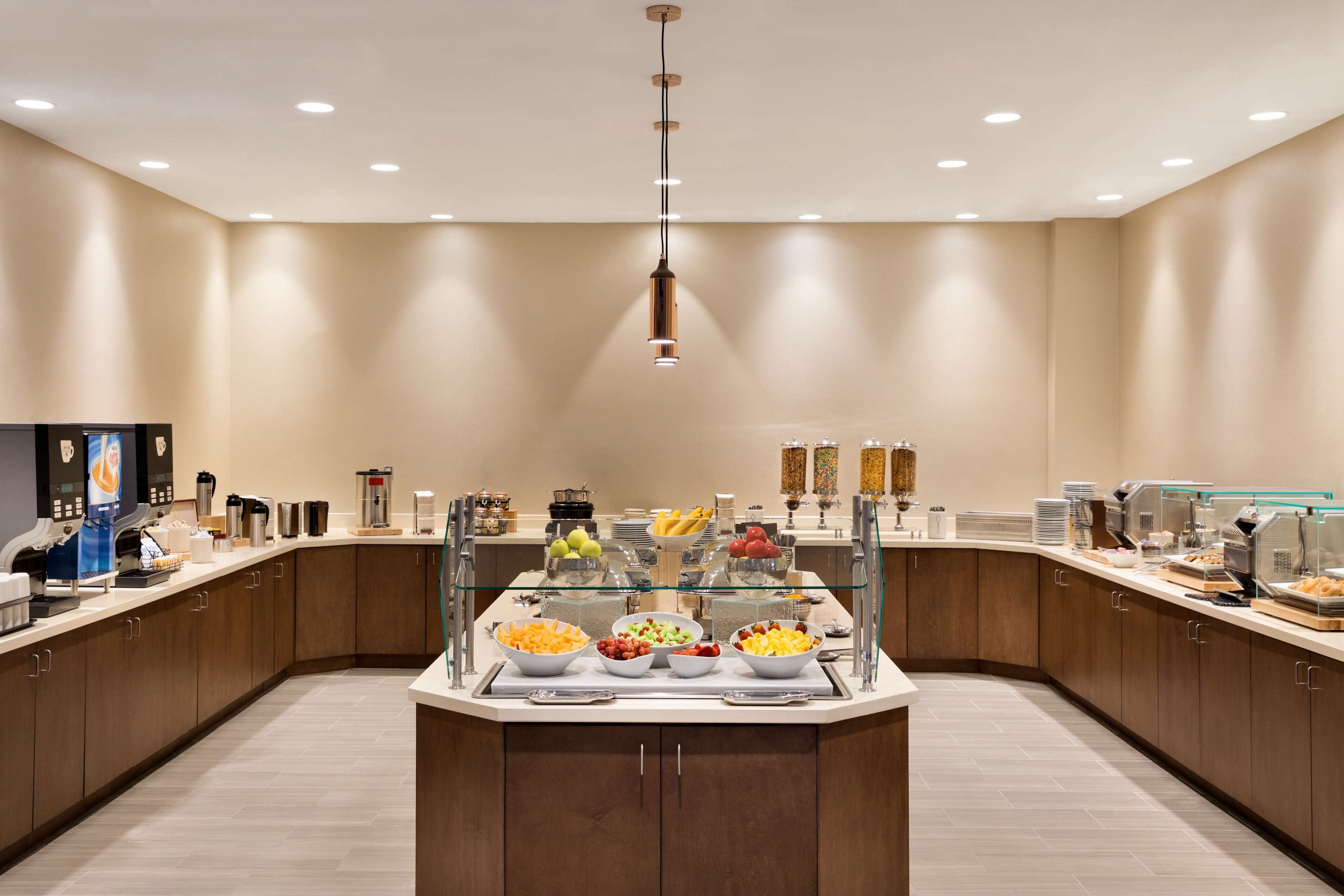 Una cocina moderna con una isla central, vitrina de vidrio y diversos alimentos.