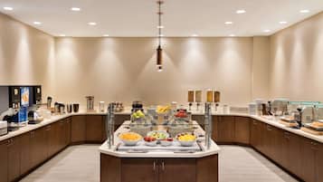 Una cocina moderna con una isla central, vitrina de vidrio y diversos alimentos.