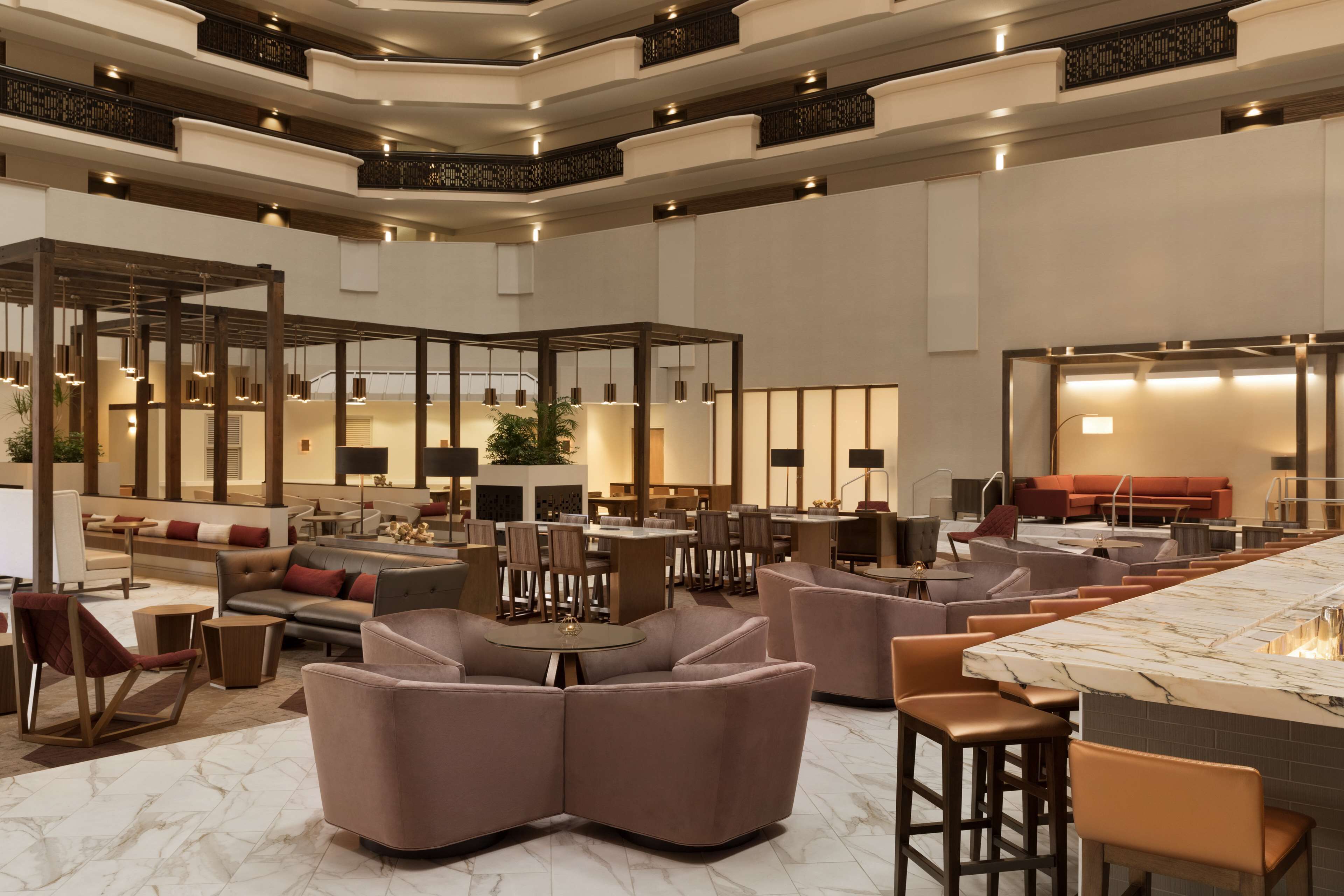 A spacious lobby with multiple seating areas, a central bar, and a staircase leading to upper floors.