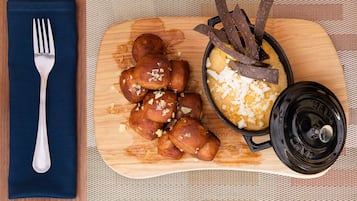A wooden board with a black pot containing a yellow dish and chocolate pieces, a fork on a blue napkin, and a wooden table.