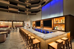 A bar area with a marble countertop, bar stools, and a variety of liquor bottles.