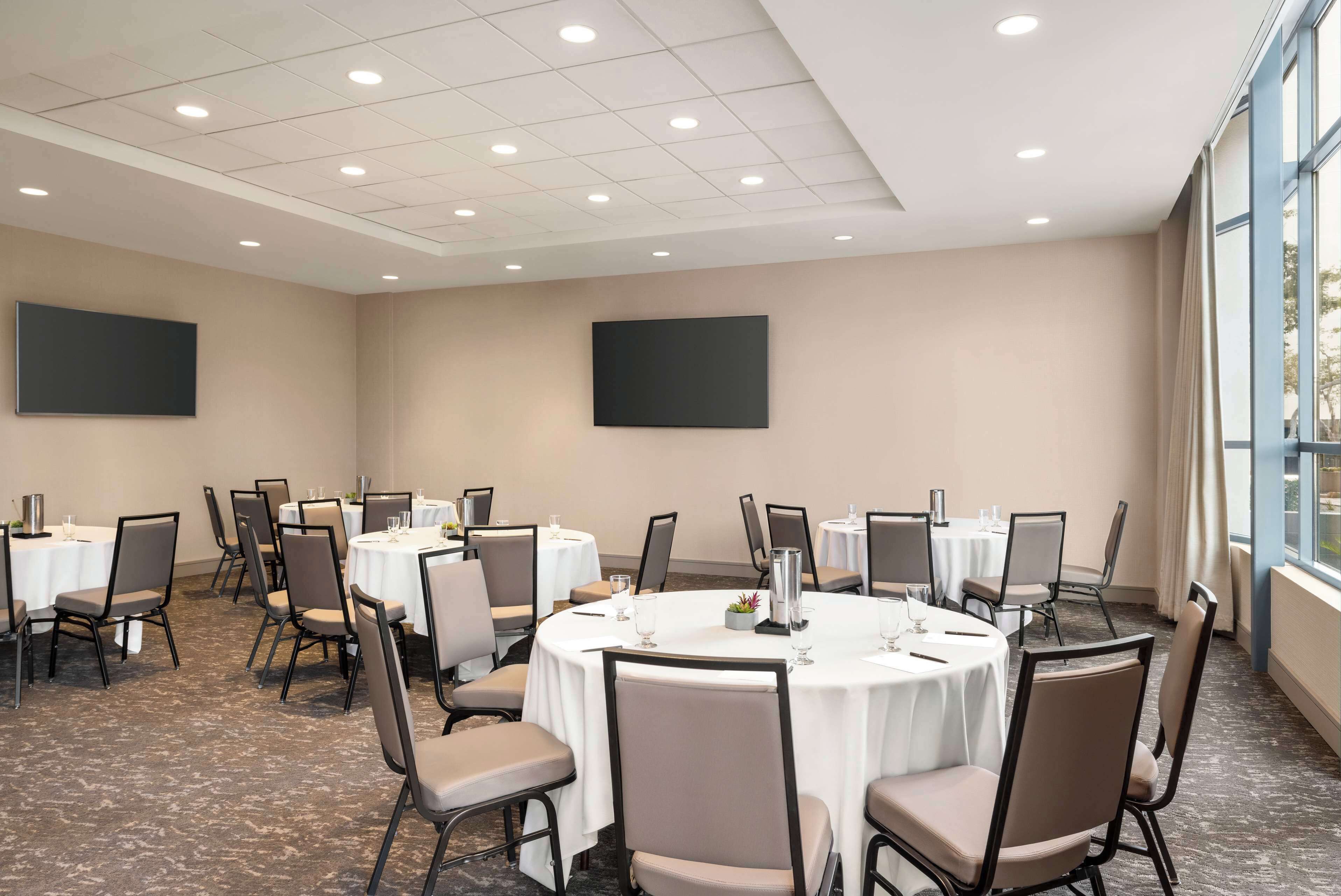 A conference room with round tables, chairs, and a carpeted floor.