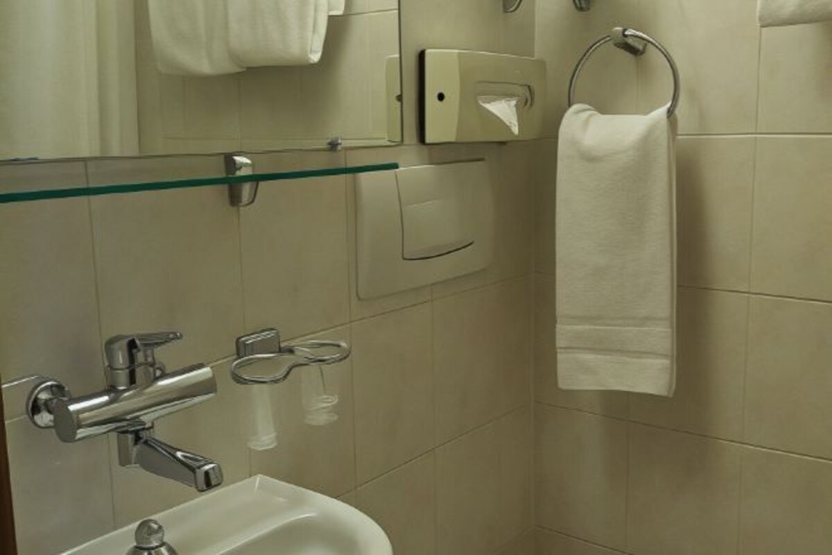 Een moderne badkamer met een douchecabine van glas, een wit wastafelmeubel en een handdoekhouder.