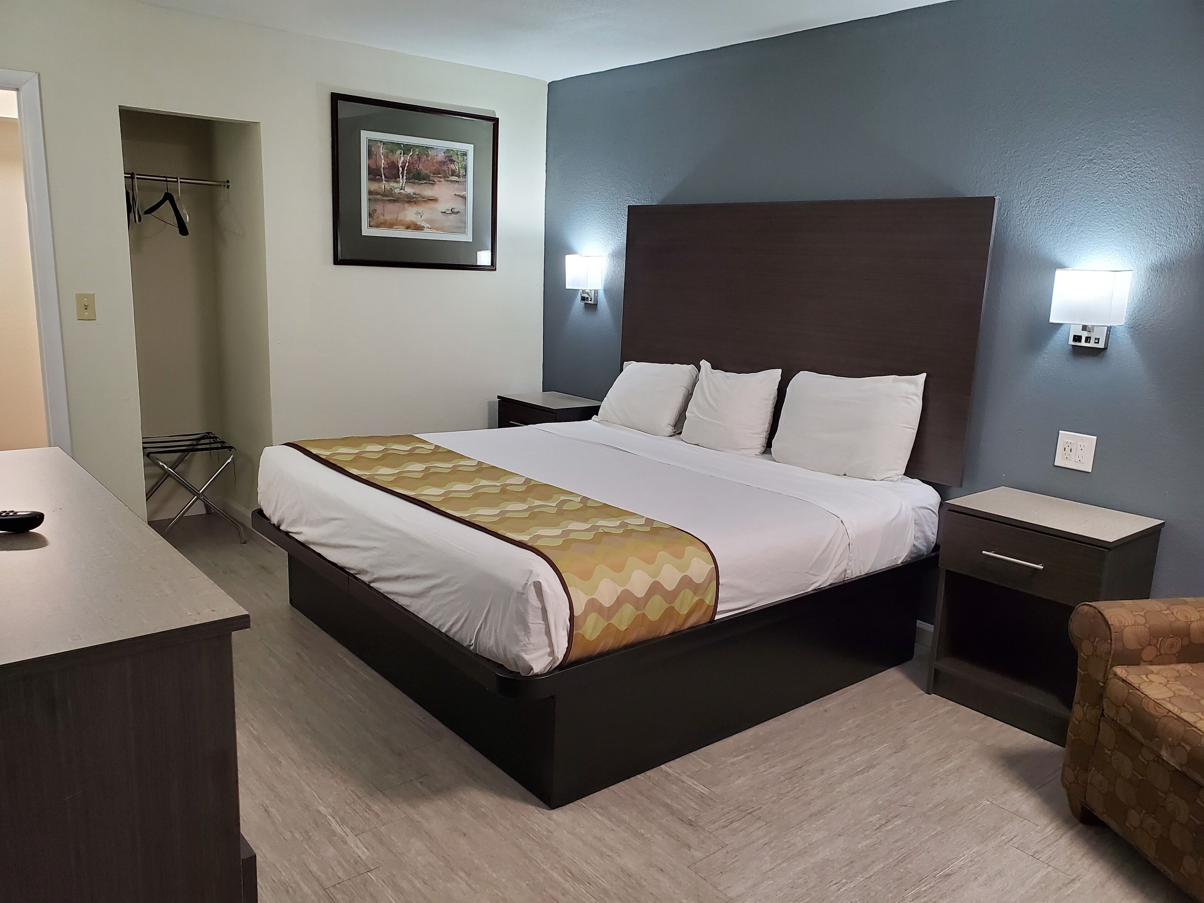 A neatly arranged hotel room with a large bed, bedside tables, a small desk, and a chair.