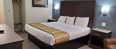 A neatly arranged hotel room with a large bed, bedside tables, a small desk, and a chair.