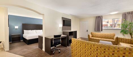 Een hotelkamer met een bed, bureau, bureaustoel, bank en een potplant.