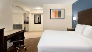 Ein Hotelzimmer mit Bett, Schreibtisch, Stuhl und einer kleinen Küche.