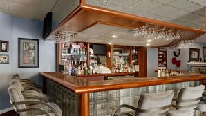 Eine Bar mit Holztresen, Barhocker und einer Auswahl an Flaschen und Gläsern.