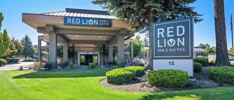 A Red Lion Inn & Suites building with a covered entrance, well-maintained lawn, and a large sign.