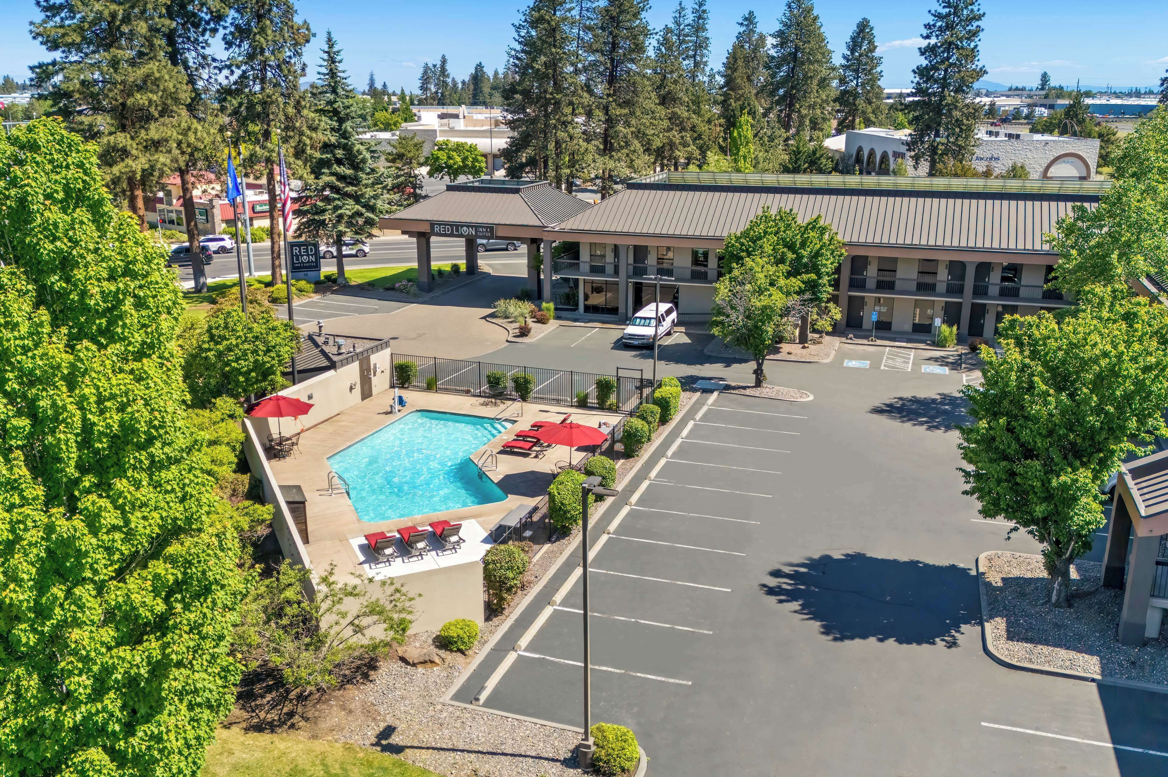 A hotel with a swimming pool, parking lot, and a building with a flat roof.