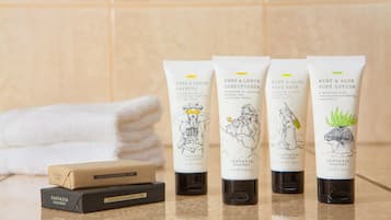 Vier tubes van Cascadia Soapery producten en twee zeepstaven op een badkamermeubel.