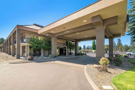 A hotel with a covered entrance, outdoor seating area, and a clear sky.. Red Lion Inn & Suites Deschutes River Bend