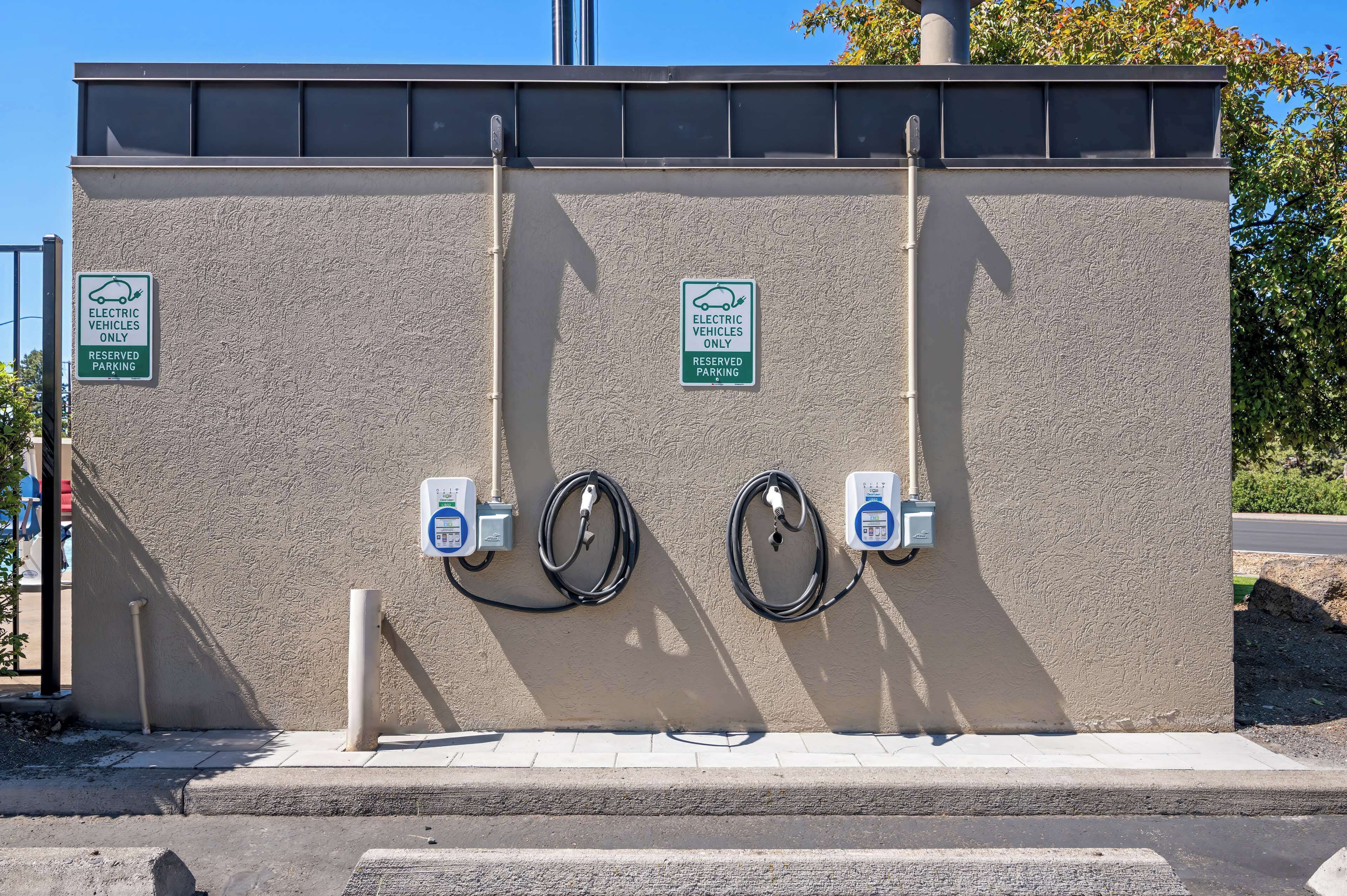 A parking structure with electric vehicle charging stations and signs indicating reserved parking for electric vehicles.