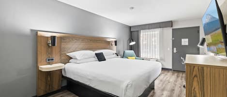 Een moderne hotelkamer met een groot bed, nachtkastjes, een bureau en uitzicht op een berg door een raam.