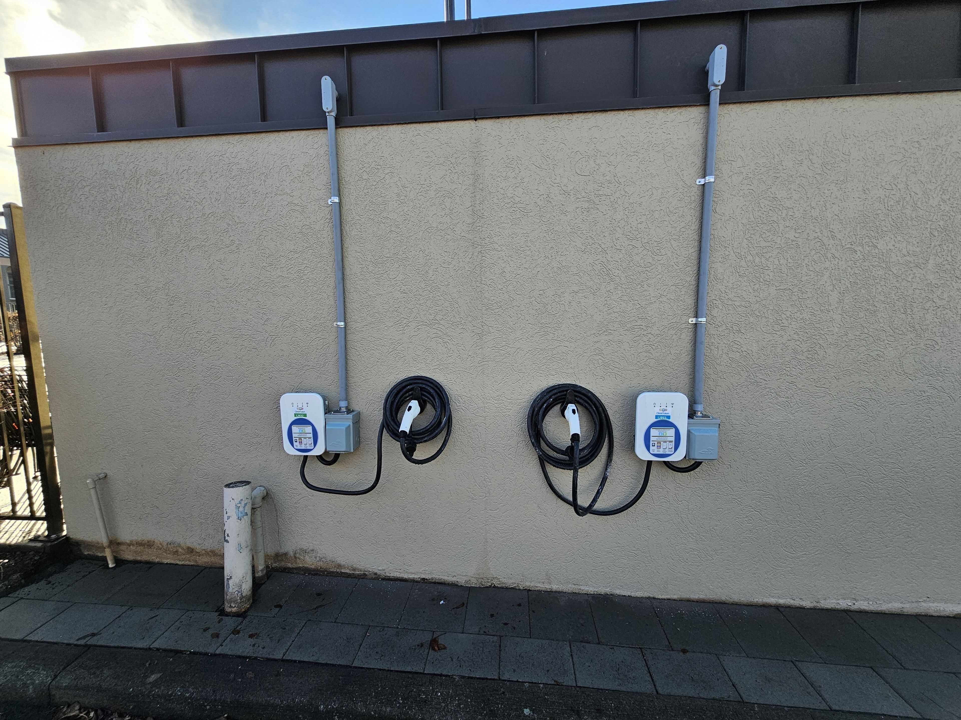 A utility wall with two electrical boxes and a coiled cable.