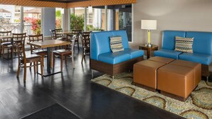 Un vestíbulo de hotel con zona de estar, mesas y un ventilador de techo.