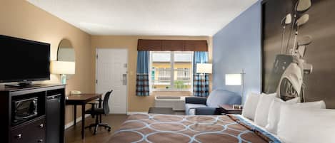 Habitación de hotel con una cama grande, un escritorio con silla, televisión y ventana con cortinas.