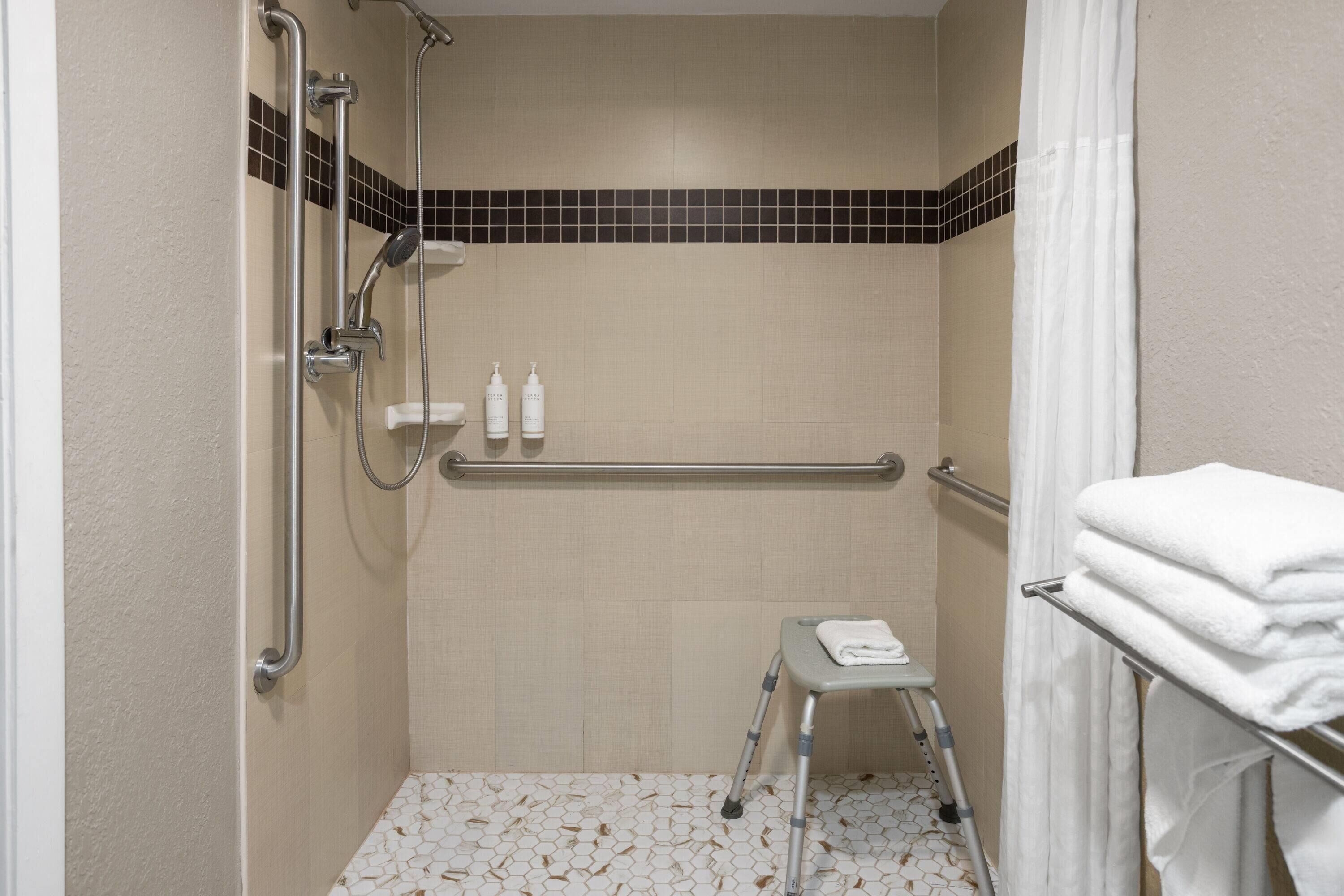 Een douche met handgrepen, een opstapje en een handdoekhouder.