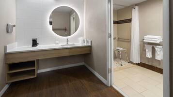 Une salle de bain moderne avec un meuble-lavabo en bois, un miroir rond, un espace douche et des toilettes.
