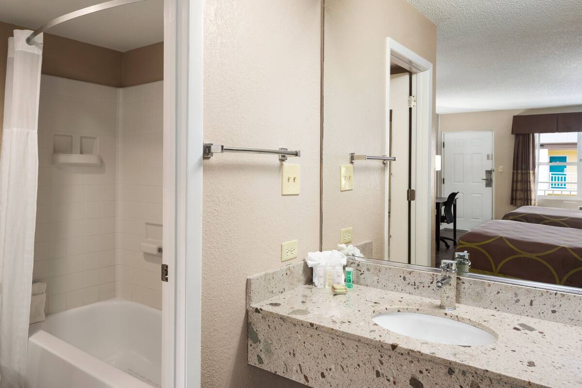 A bathroom with a bathtub, a sink, and a mirror.