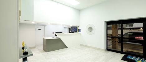 A reception area with a desk, a computer, and a wall-mounted fan.