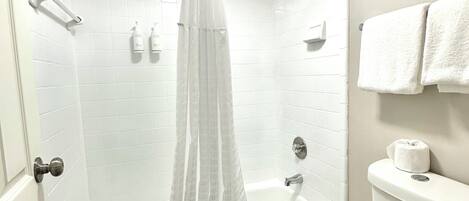 A modern bathroom with a bathtub, shower, toilet, and a towel rack.