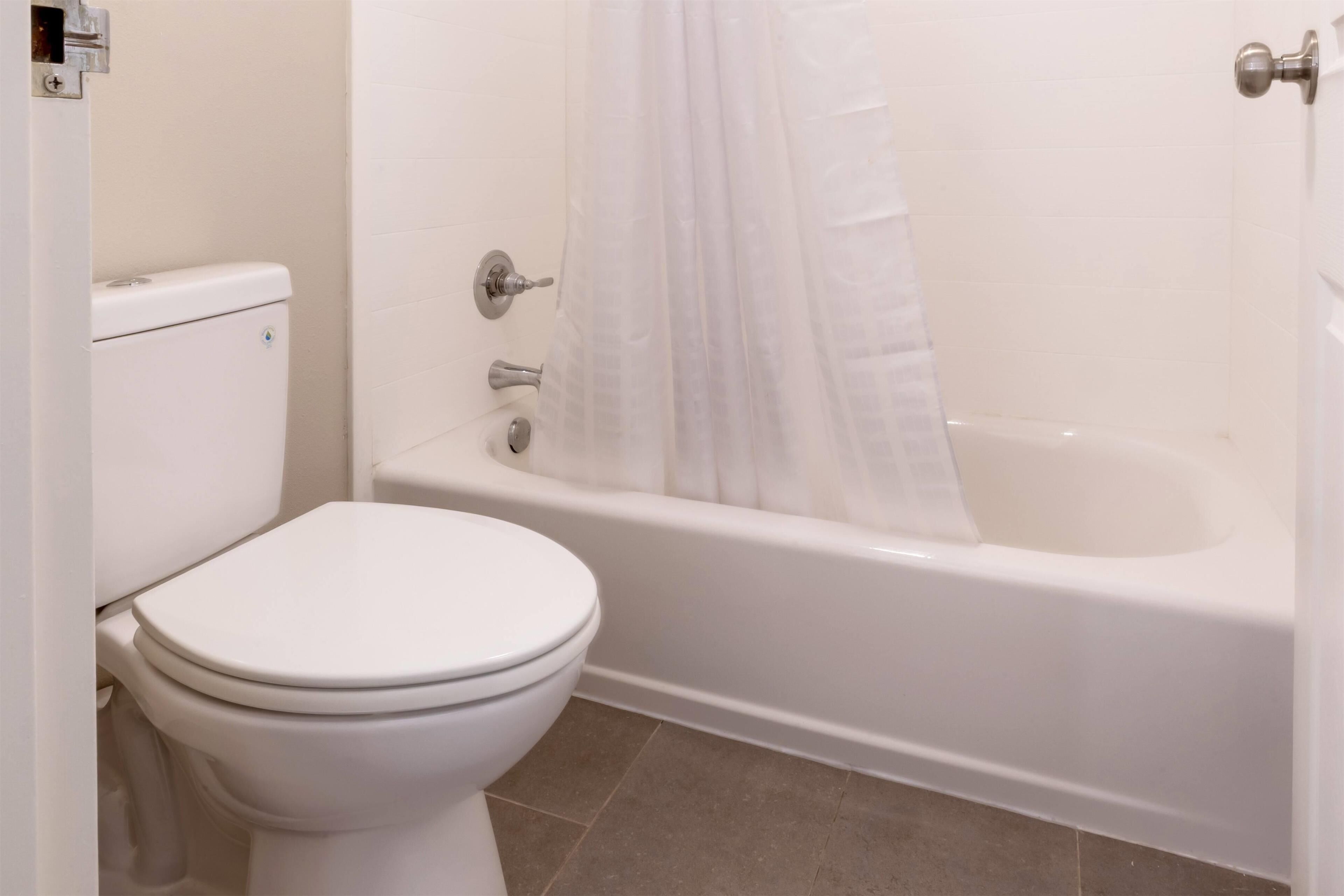 Un baño con inodoro, bañera y cortina de ducha.
