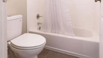 Un baño con inodoro, bañera y cortina de ducha.