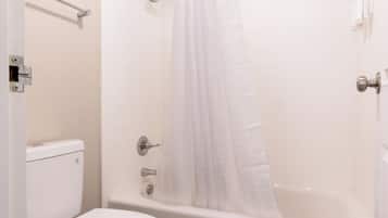 Une salle de bain équipée de toilettes, d’une baignoire et d’un rideau de douche.