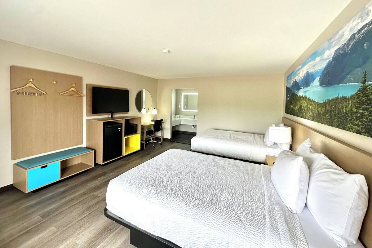 Ein Hotelzimmer mit einem großen Bett, einem Schreibtisch mit Stuhl, einem Fernseher, einem Kleiderschrank und einem Badezimmer.