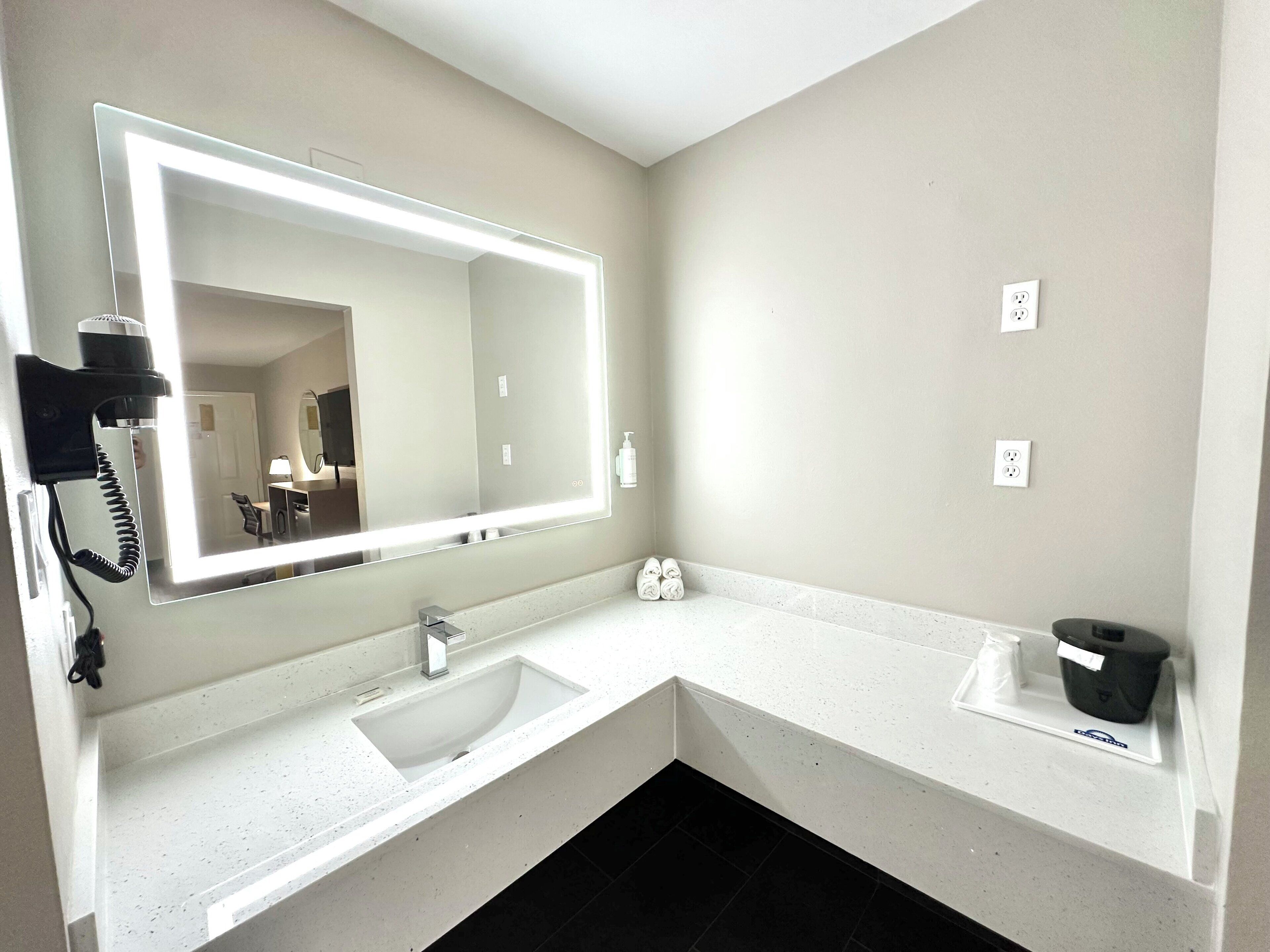 Un baño moderno con un espejo grande, un lavabo y un perchero para toallas.