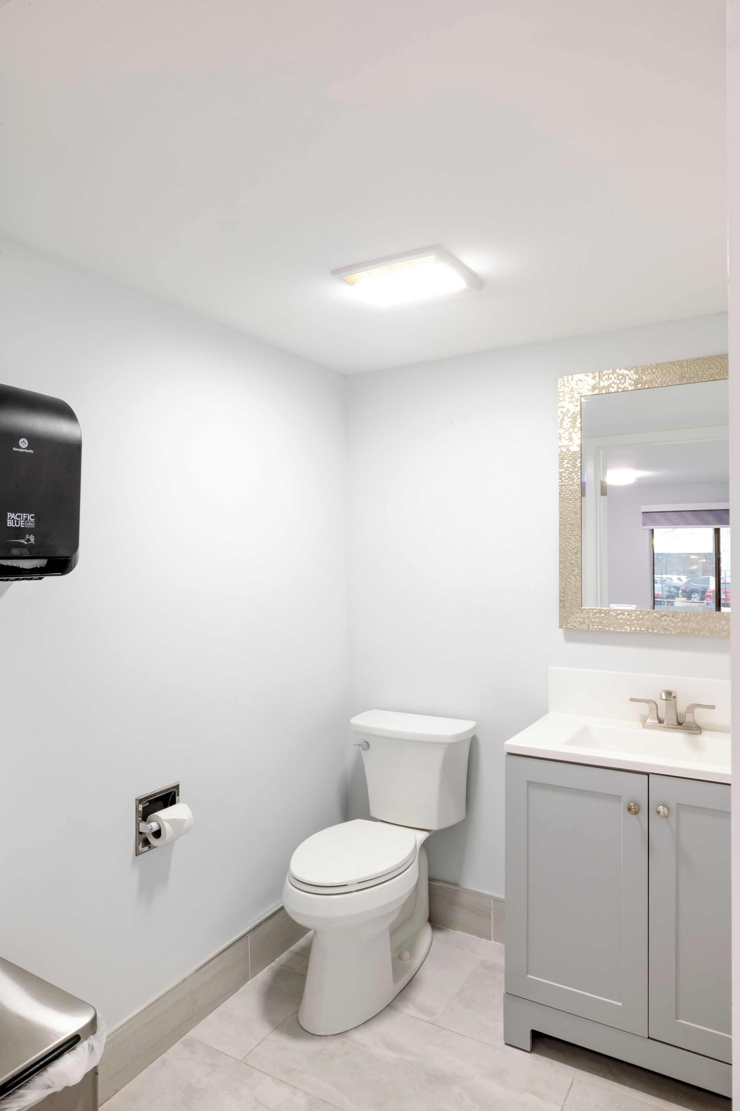 A bathroom with a toilet, a sink with a mirror, and a hand dryer.