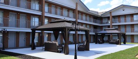 A multi-story hotel with outdoor seating areas and a covered patio.