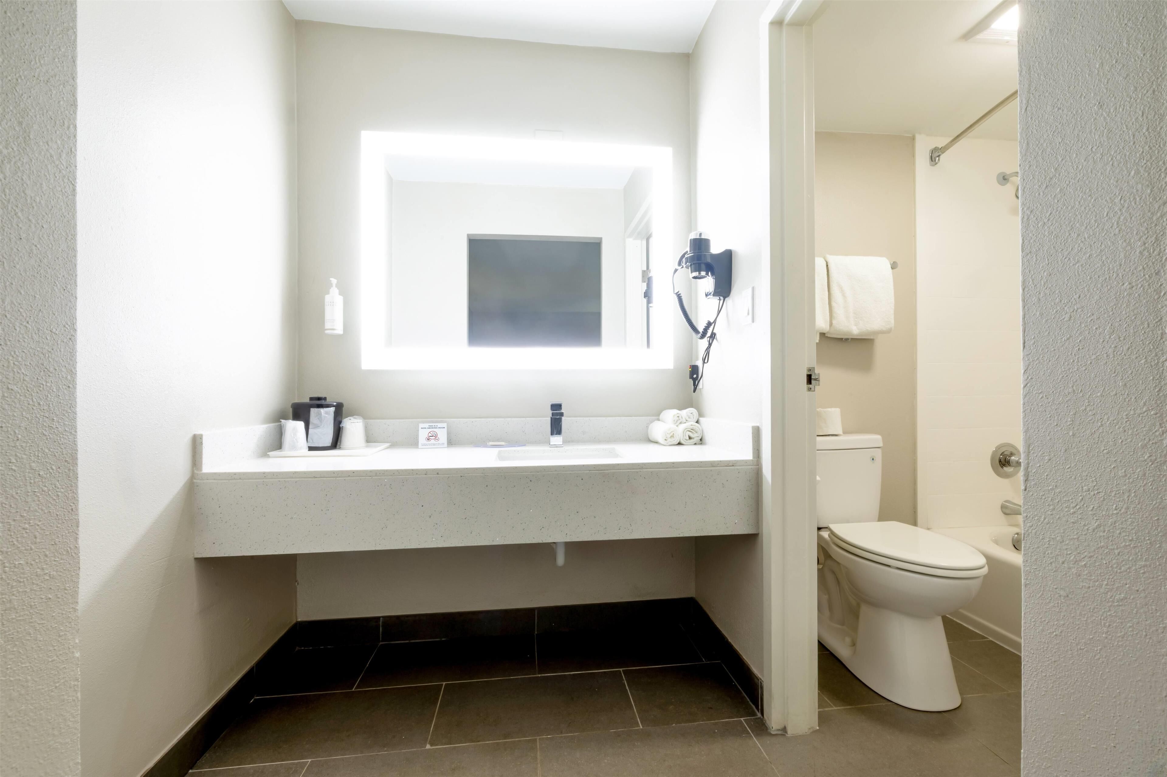 A modern bathroom with a white sink, a mirror, a toilet, and a shower area.