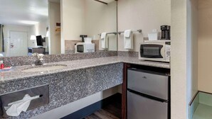 Une cuisine moderne dotée de plans de travail en granit, d’un évier encastré, d’un réfrigérateur, d’un four à micro-ondes et d’une machine à caf é.