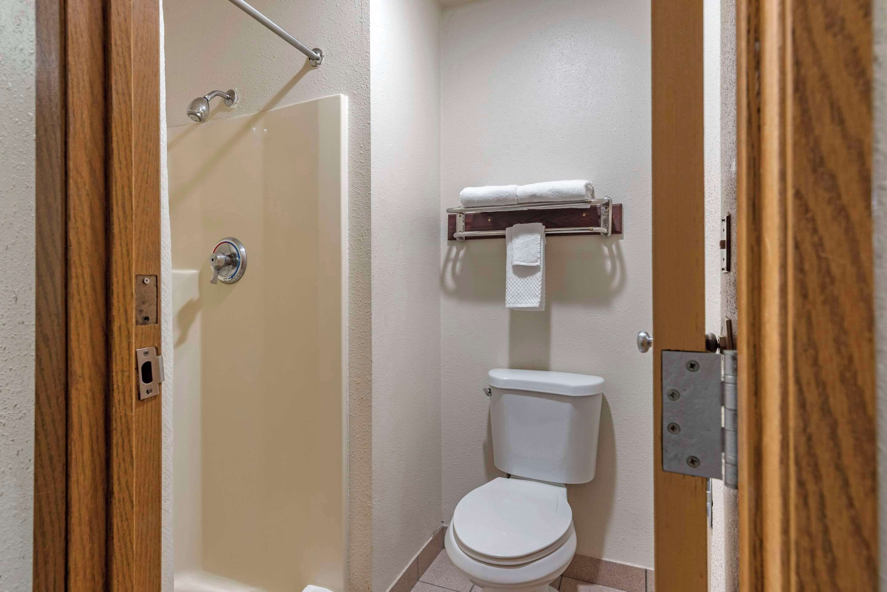 Un baño con ducha, inodoro y toallero.