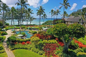 A resort with a pool, palm trees, and a view of the ocean. - Kauai Coast at the Beachboy (Kapaa)