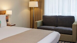 A hotel room with a large bed, a desk, a chair, and a sofa. - Holiday Inn Colchester by IHG (Colchester)