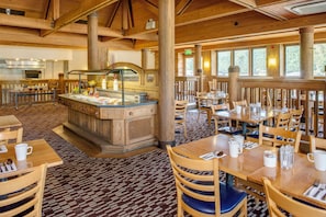 A restaurant with wooden interiors, a buffet counter, and dining tables with chairs.