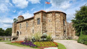 A historic stone building with a flag, a dome, and a garden with colorful flowers. - Holiday Inn Colchester by IHG (Colchester)