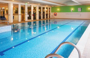 An indoor swimming pool with clear water, marked lanes, and safety equipment.