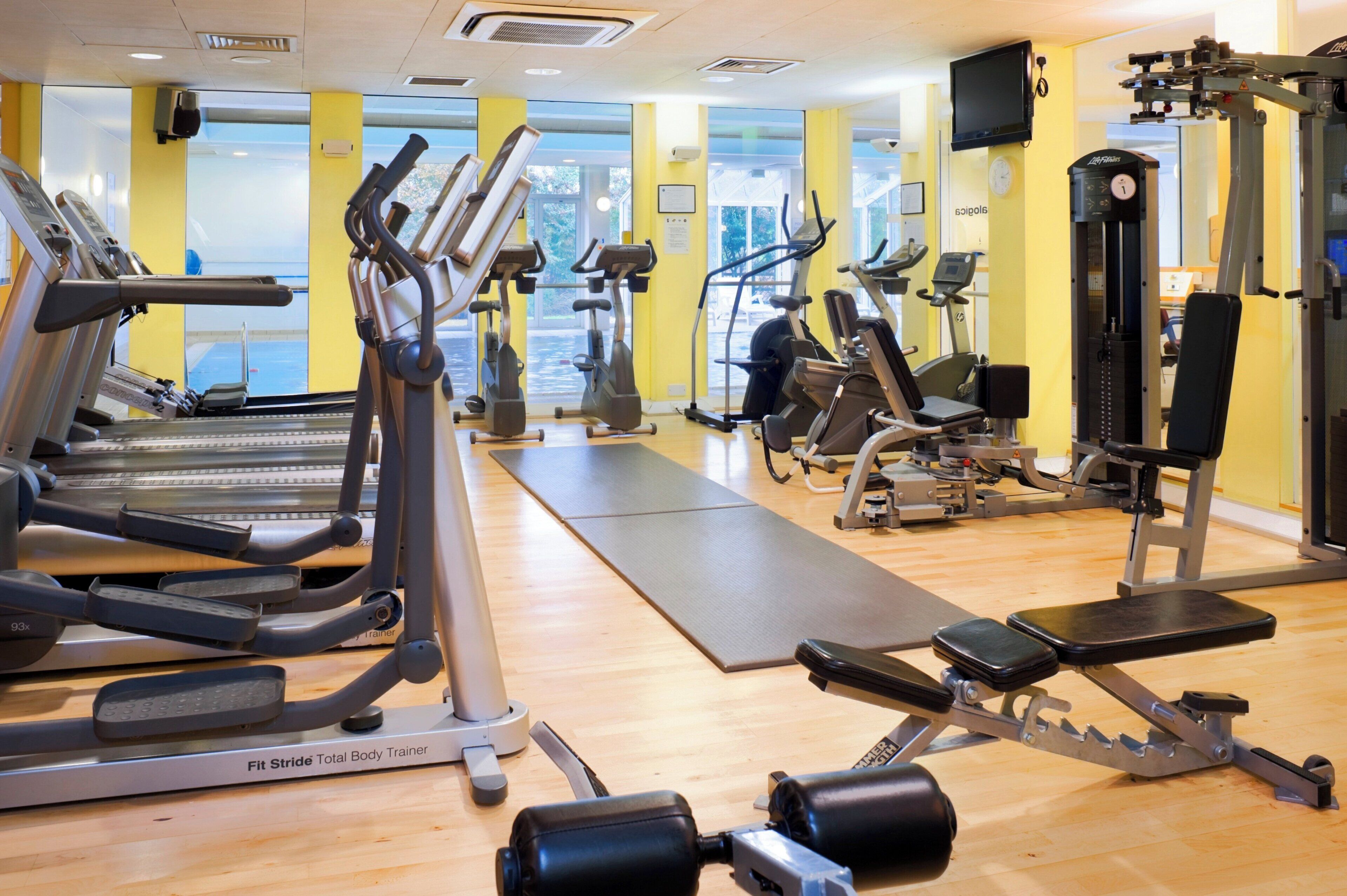 A gym with various exercise equipment including treadmills, elliptical machines, and weight training apparatus.