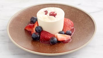 Un postre en un plato con fresas y arándanos.